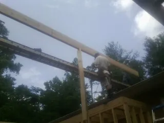Carpenter setting a ridge beam over a new addition frame — Ice Dam Removal by Roofing Brothers in Sunny Side