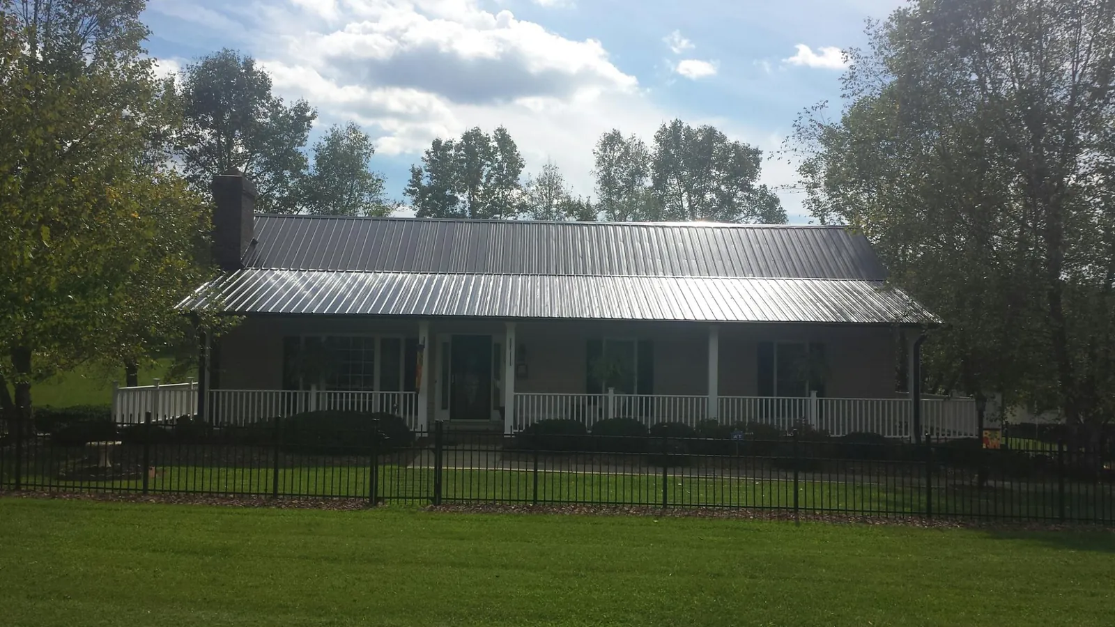 Gray metal roof on a brick ranch with a full width front porch — Gutter Guard Installation work by our crew in Sunny Side