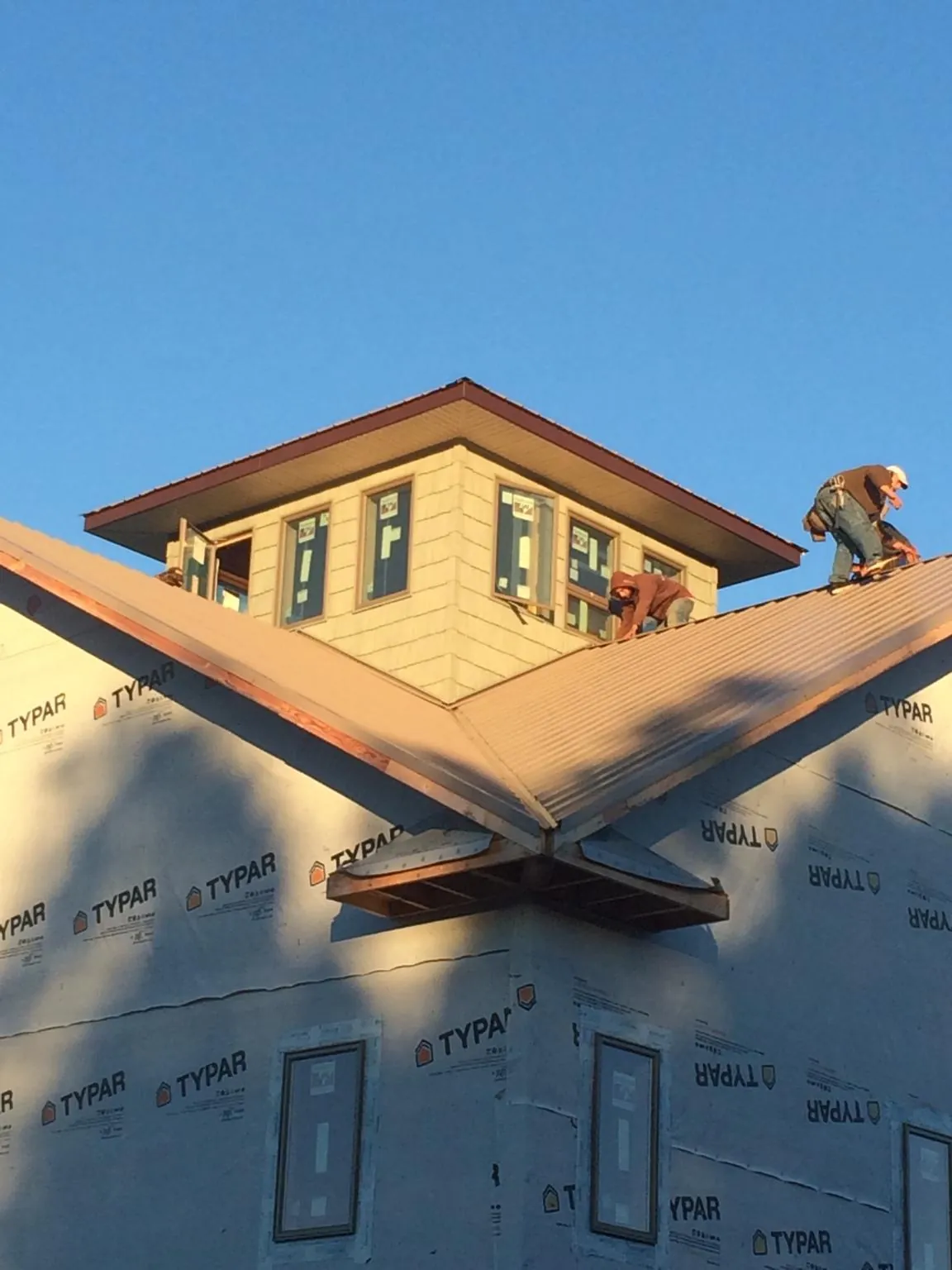 Roofers working around a rooftop cupola on a new metal roof at sunset — Roof Waterproofing in Sunny Side by Roofing Brothers